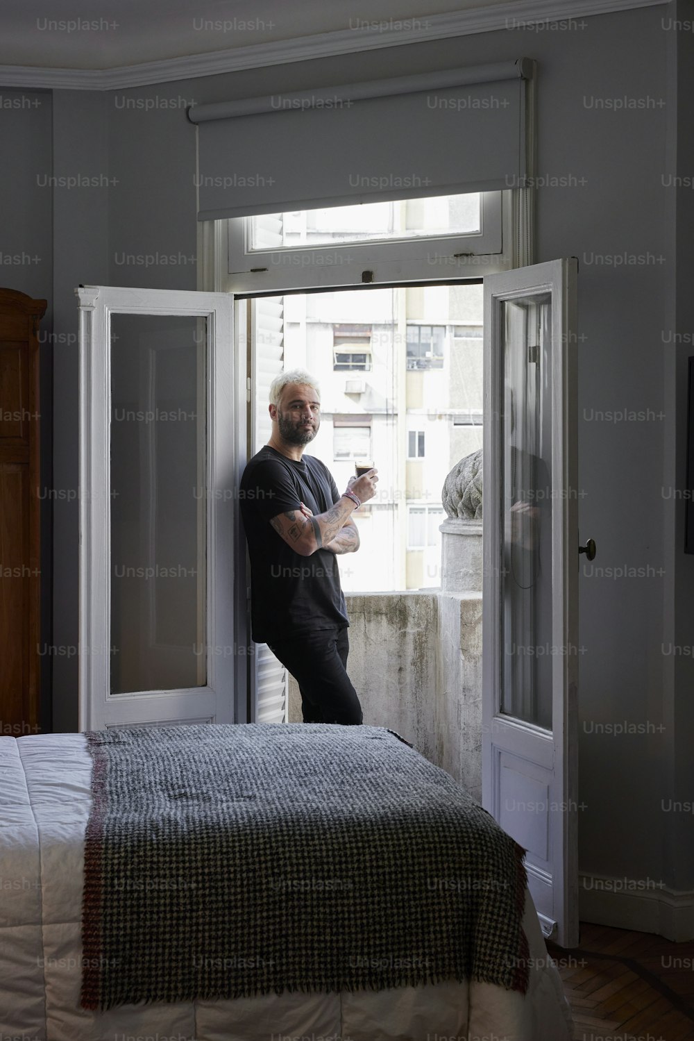 Un hombre parado en un dormitorio mirando por una ventana