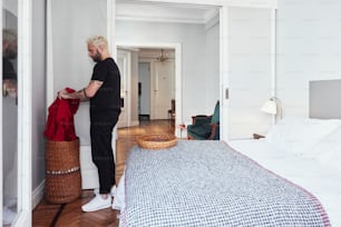 a man standing next to a bed in a bedroom