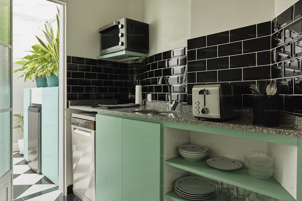 uma cozinha com armários verdes e azulejos pretos e brancos