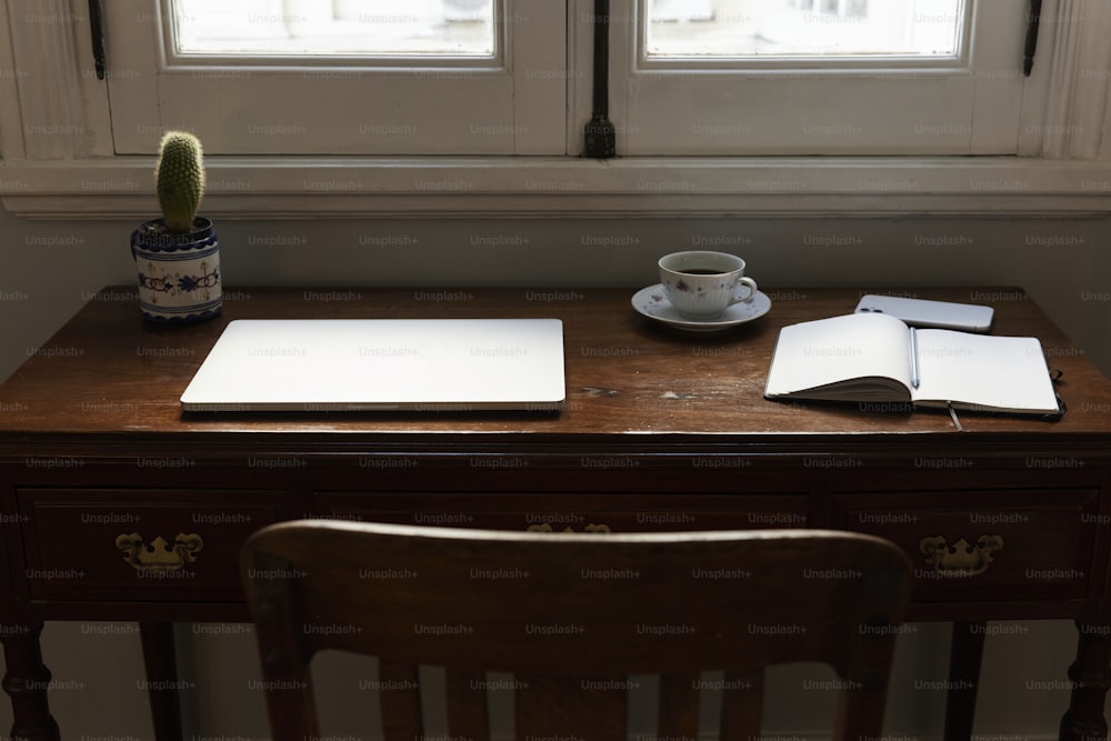 una scrivania con una tazza di caffè e un taccuino su di esso