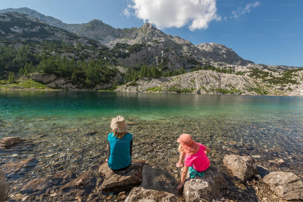 a couple of kids sitting on top of rocks near a lake