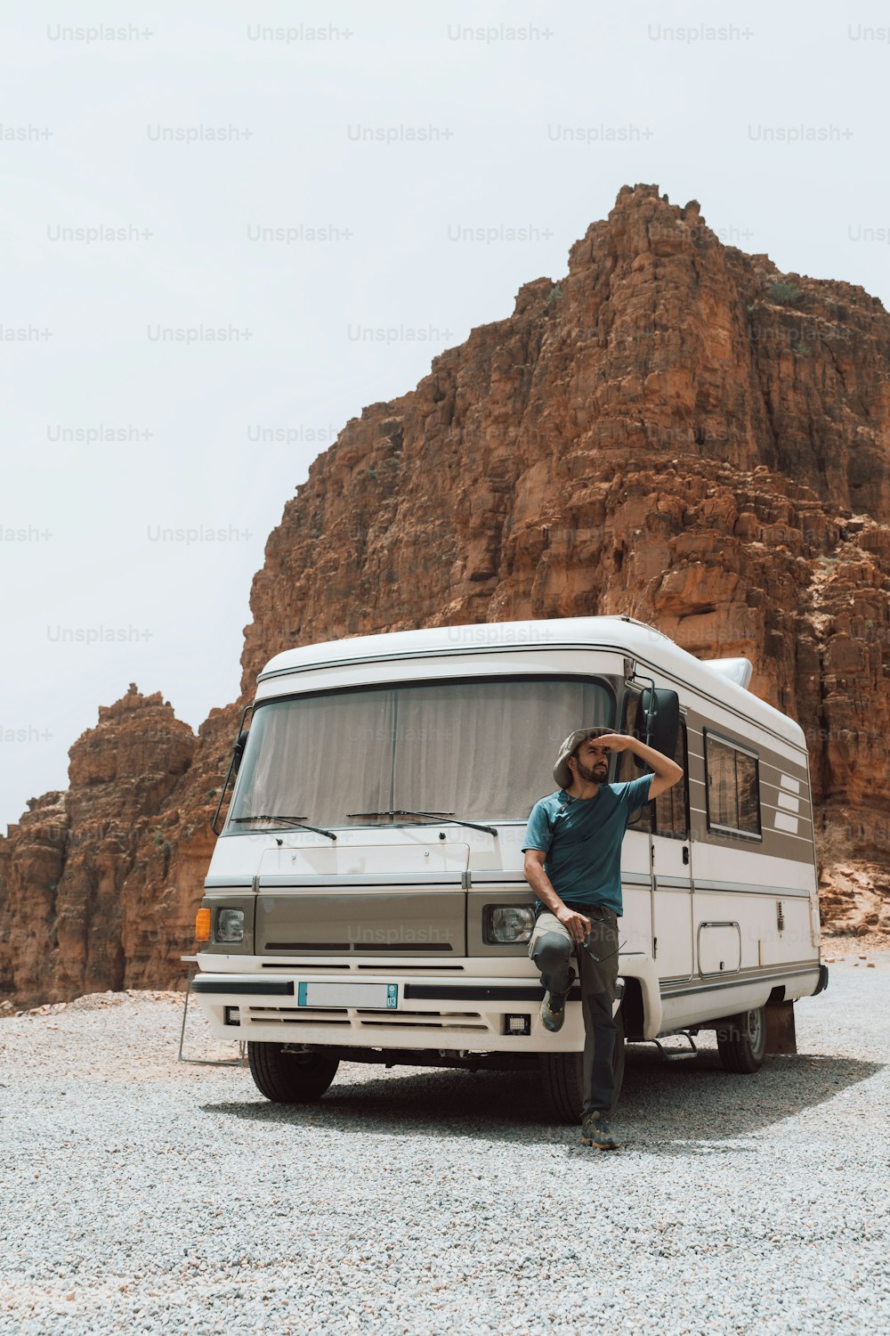 a man sitting on the front of a van in front of a mountain