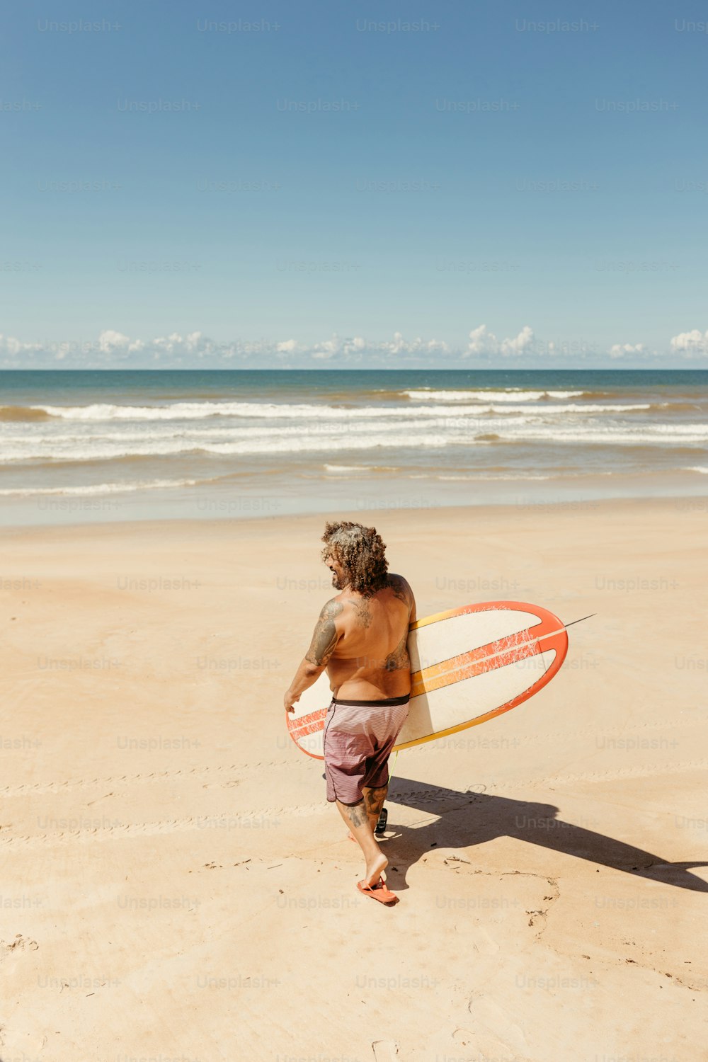서핑보드를 들고 해변을 걷고 있는 남자