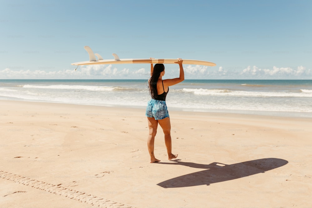 a woman holding a surfboard over her head on the beach