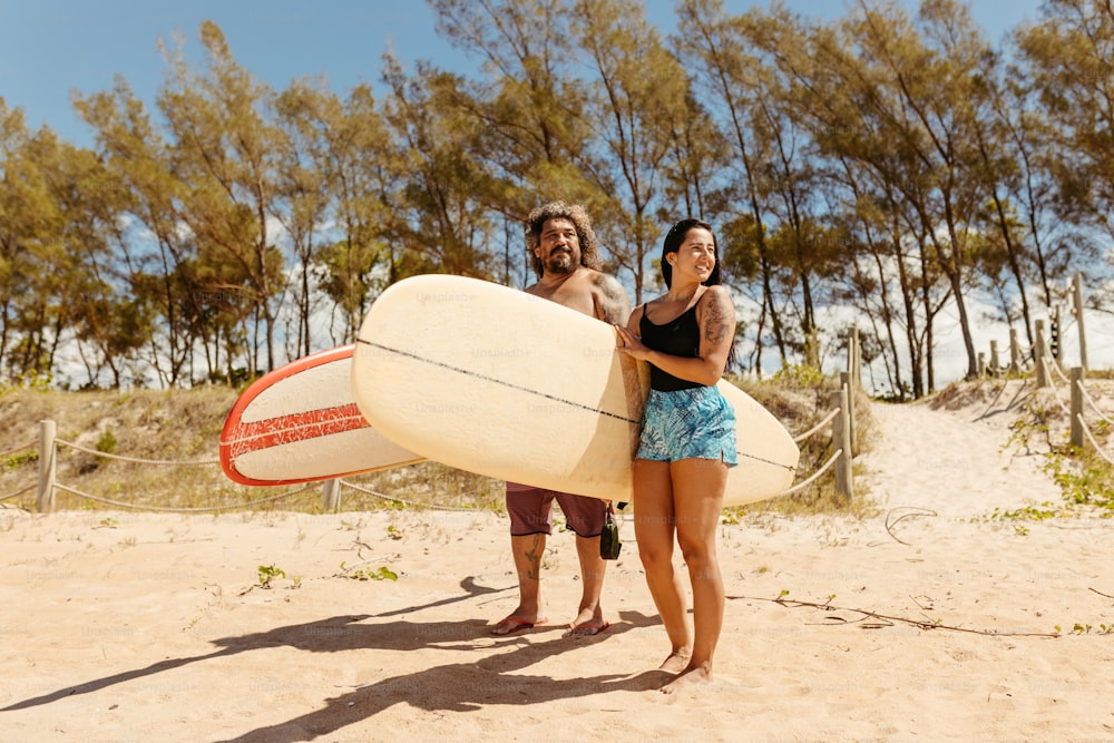 a man and a woman holding a surfboard on the beach