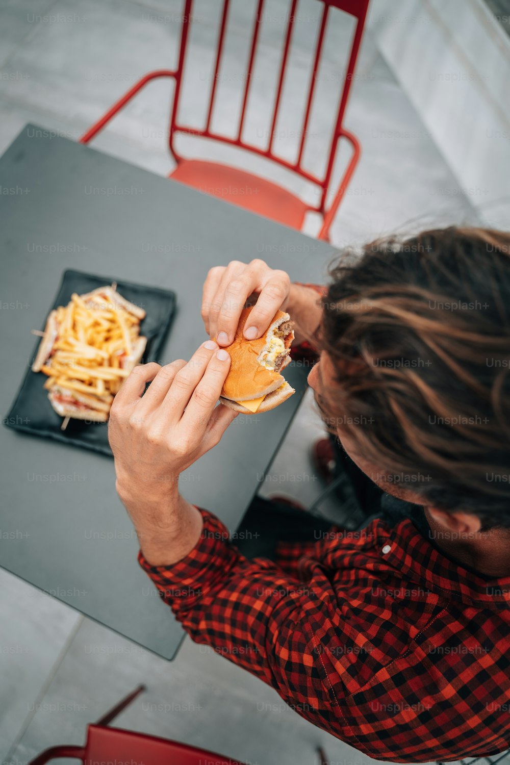 Un hombre sentado en una mesa comiendo un sándwich