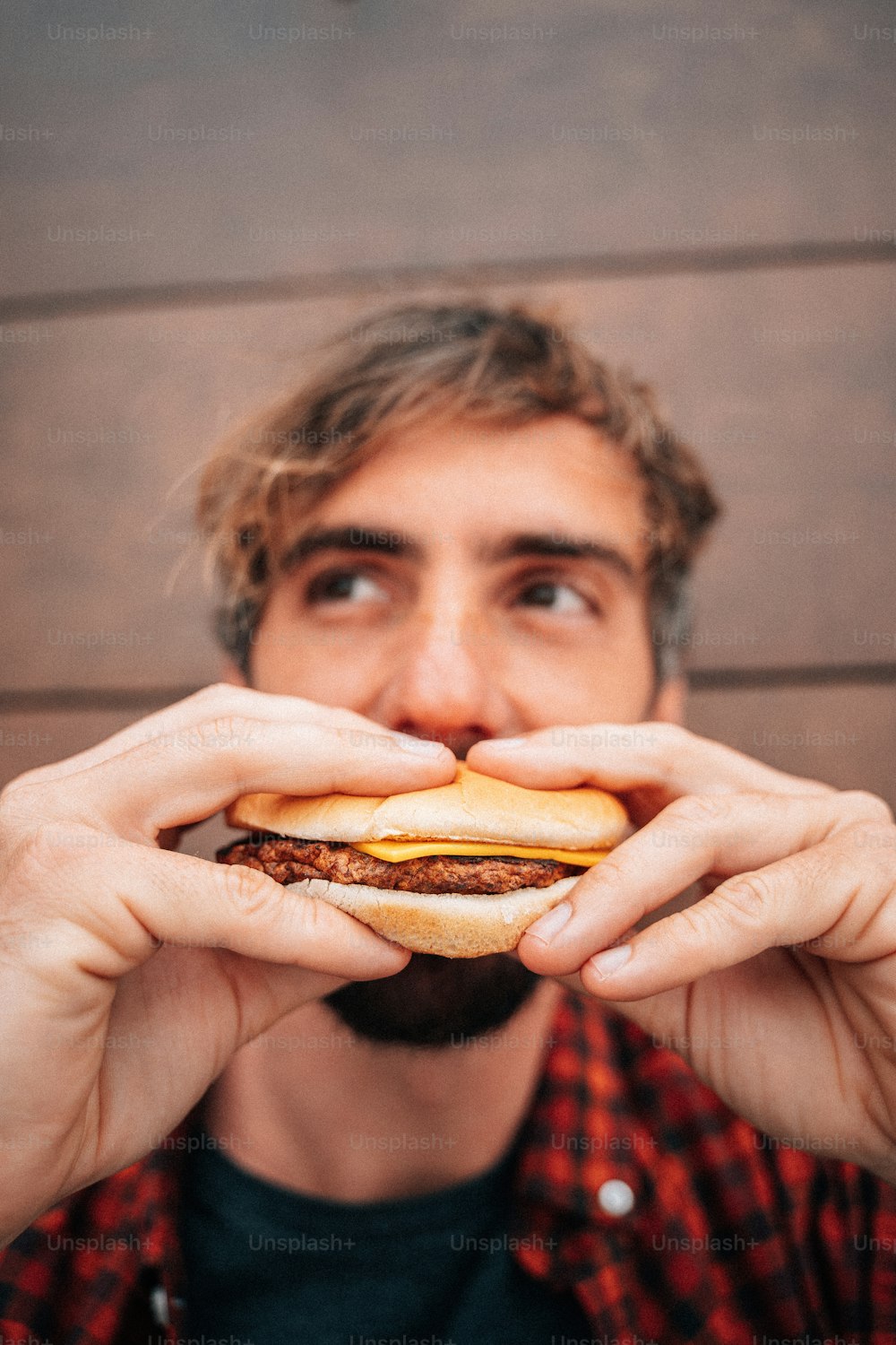 um homem segurando um hambúrguer na frente de seu rosto