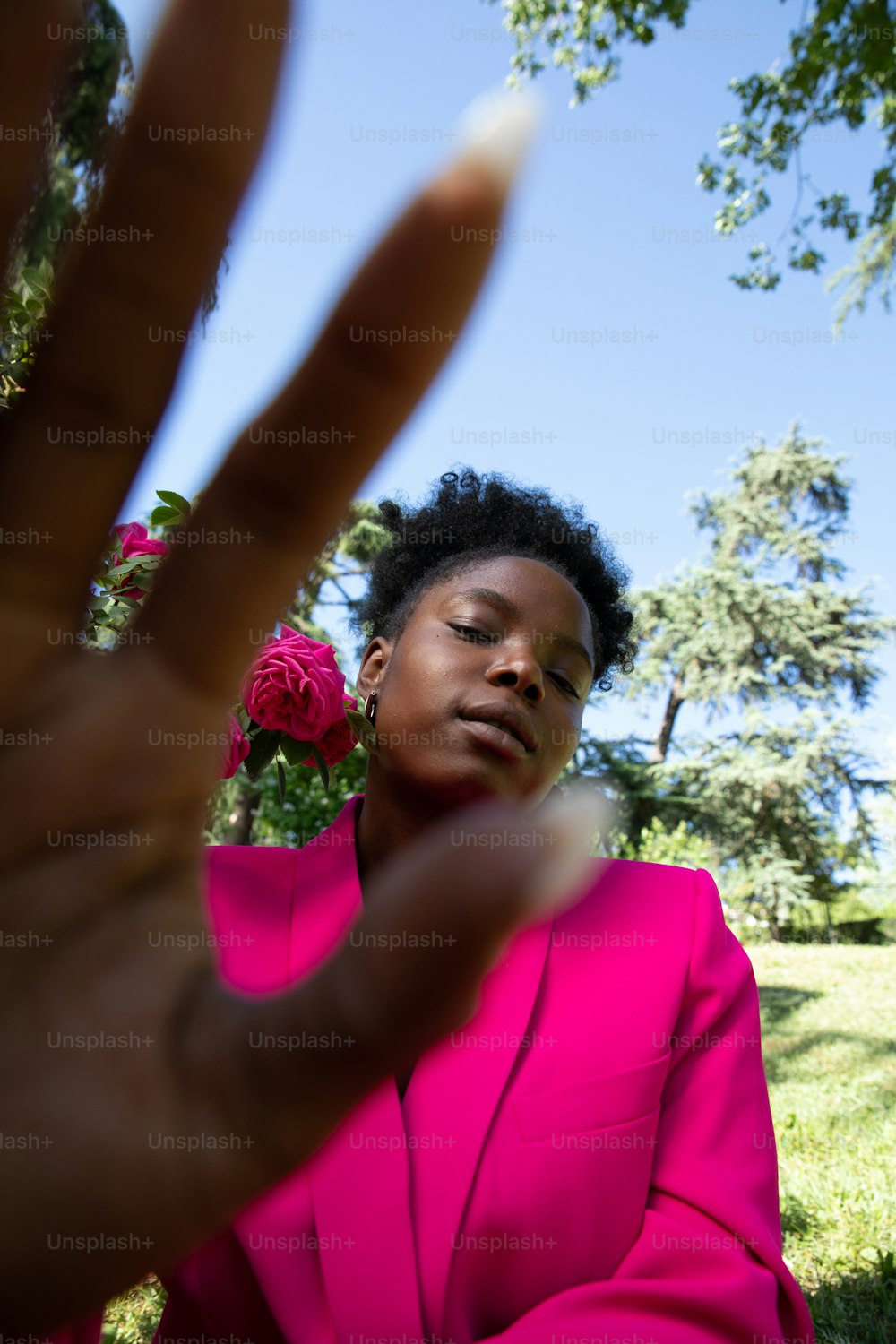 Una mujer con un traje rosa sosteniendo un signo de paz