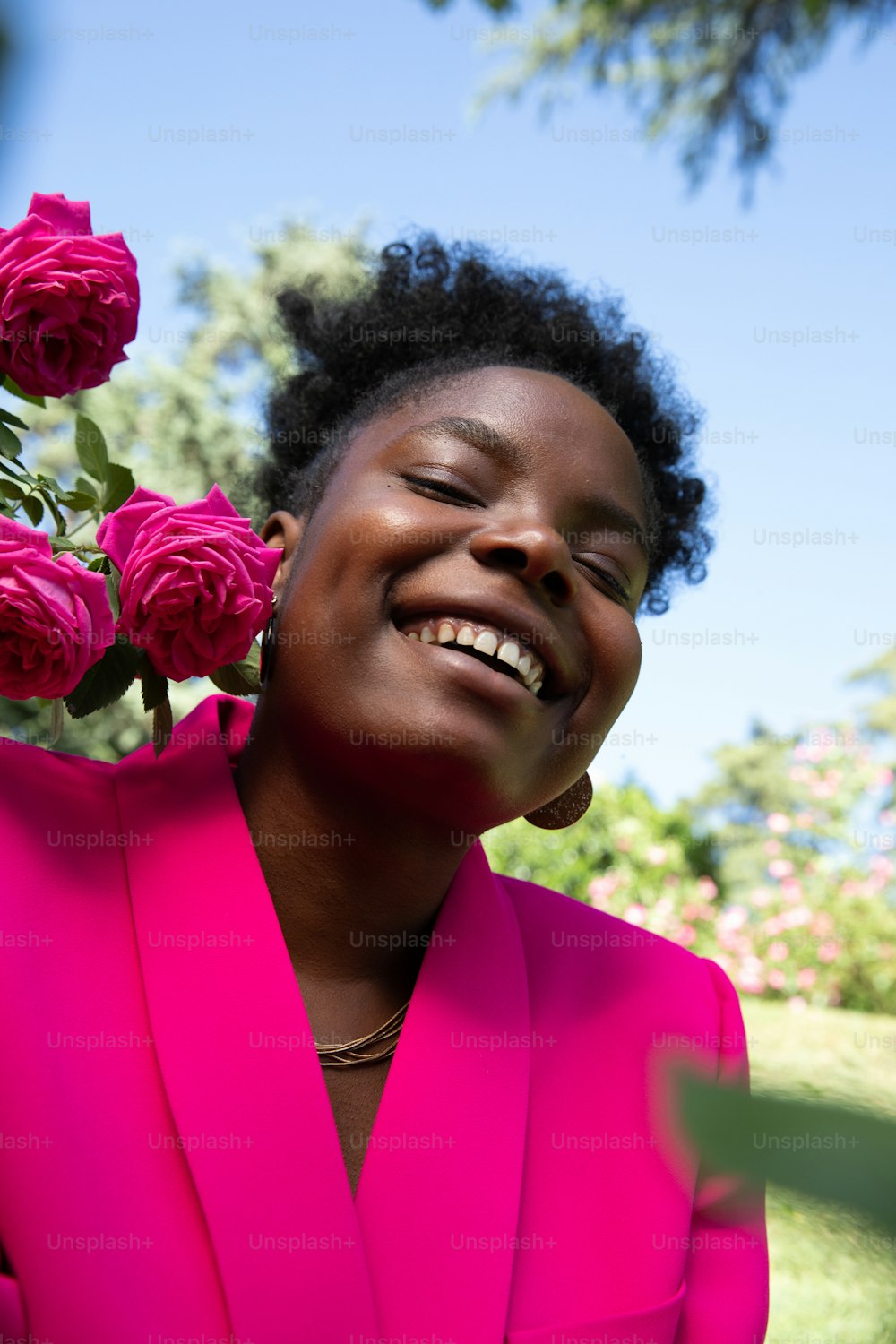 a woman in a bright pink suit smiles at the camera