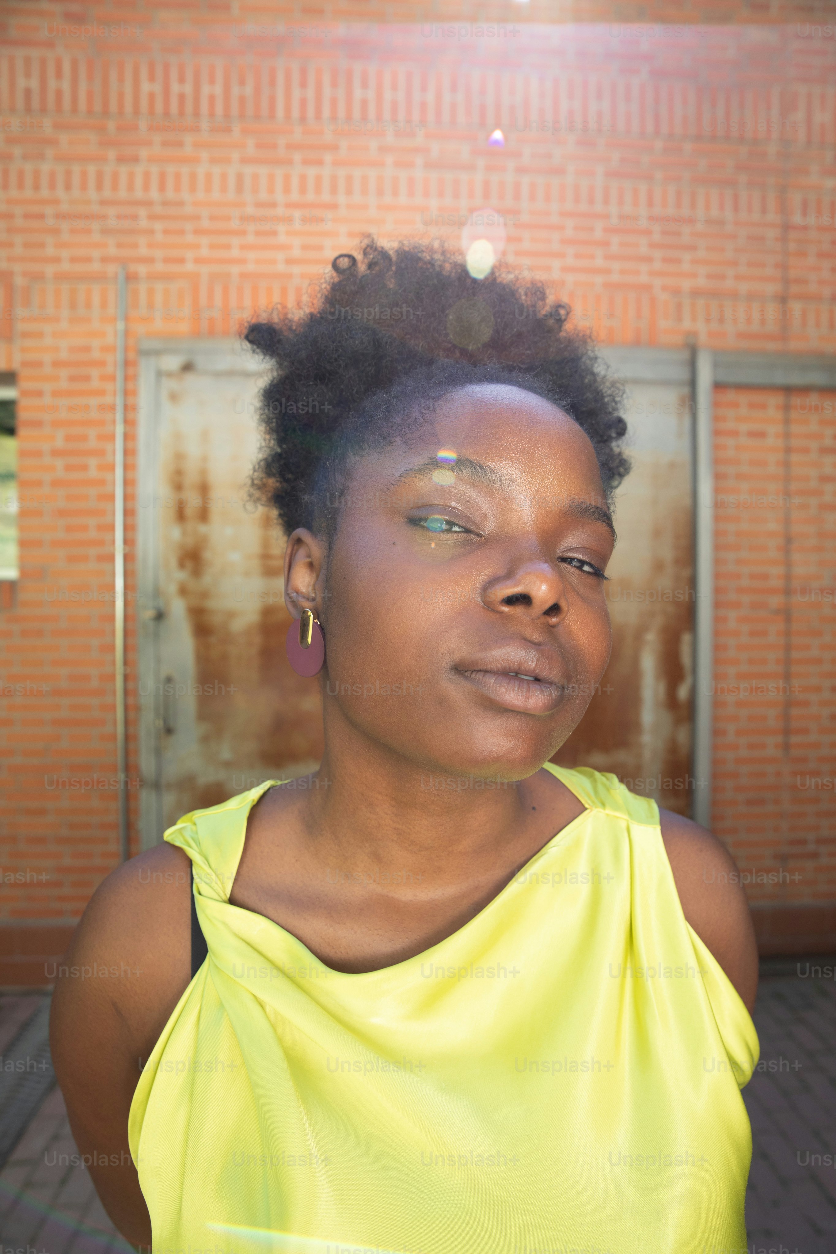 レンガ造りの建物の前に立つ黄色いトップの女性