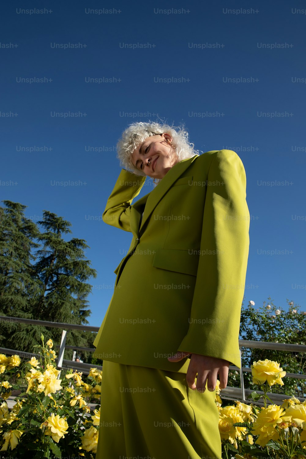 a woman in a yellow suit is standing in a field of flowers