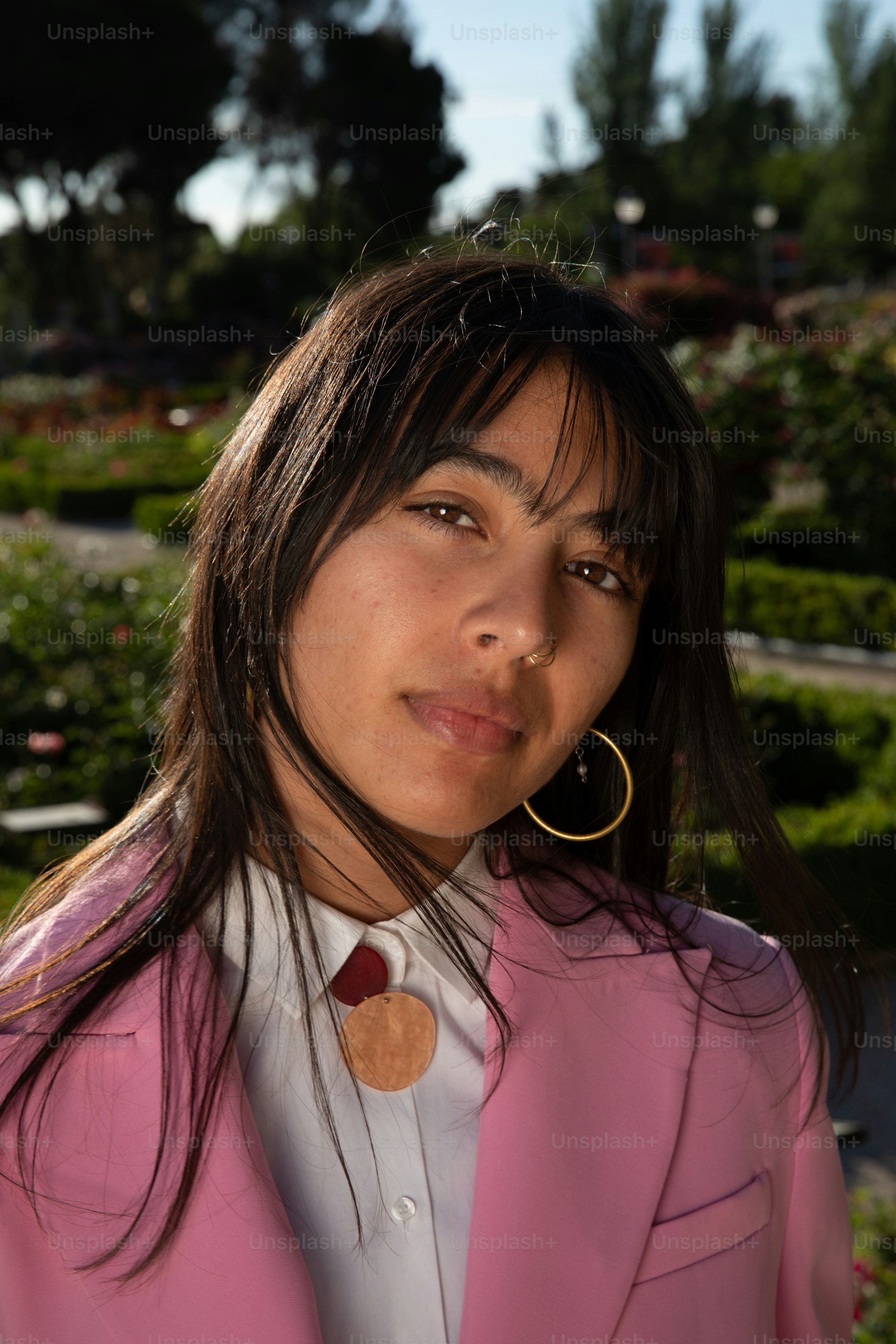 uma mulher em uma jaqueta rosa e brincos de aro dourados