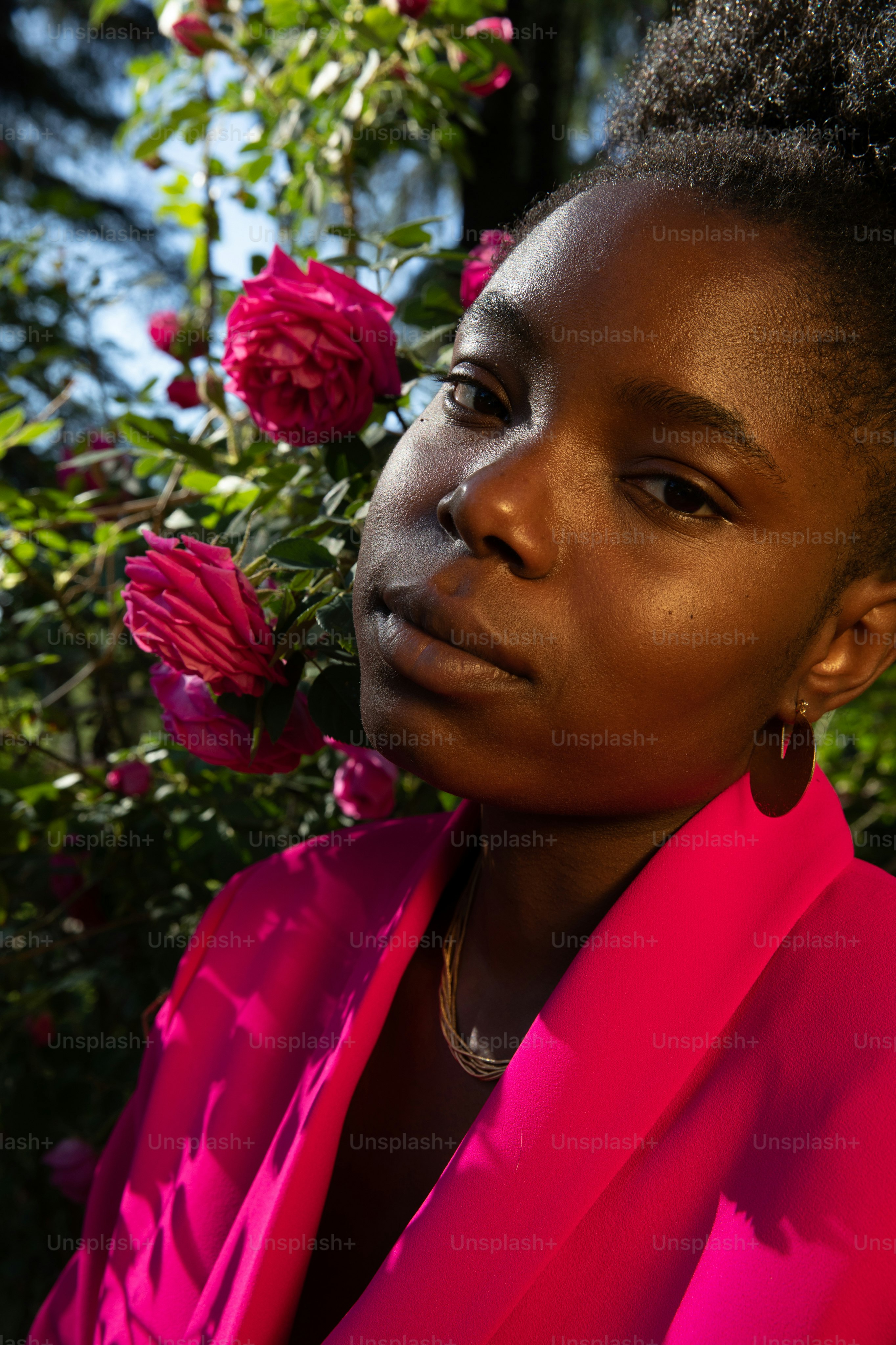 A woman in a pink dress standing in front of flowers photo – Woman ...