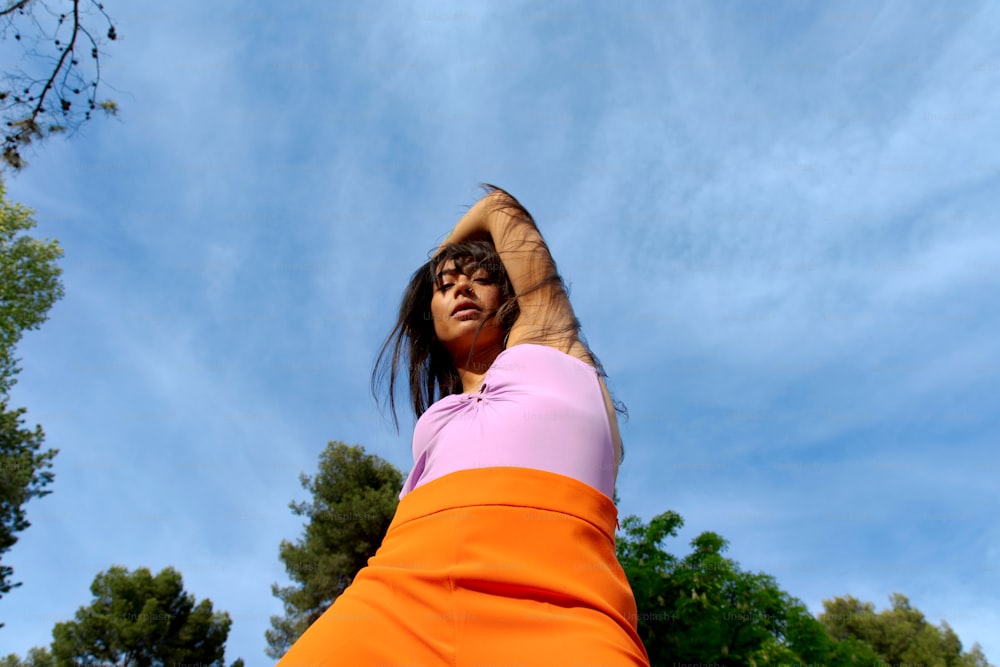 Eine Frau in einem orange-rosa Kleid lässt einen Drachen steigen