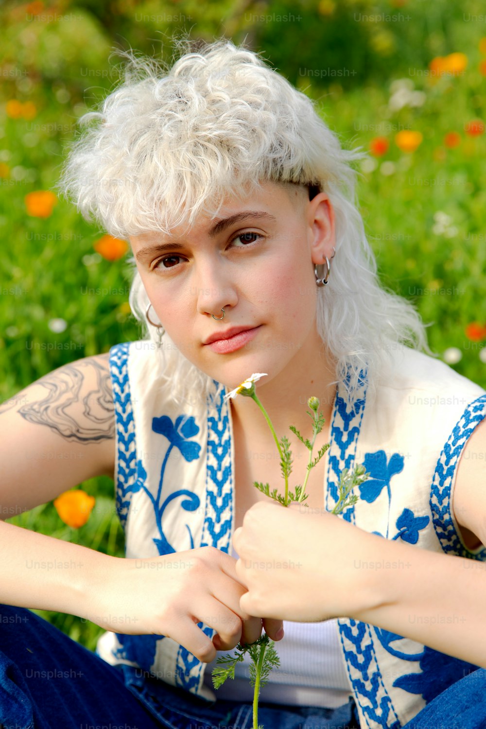 a woman sitting in a field with a flower in her hand