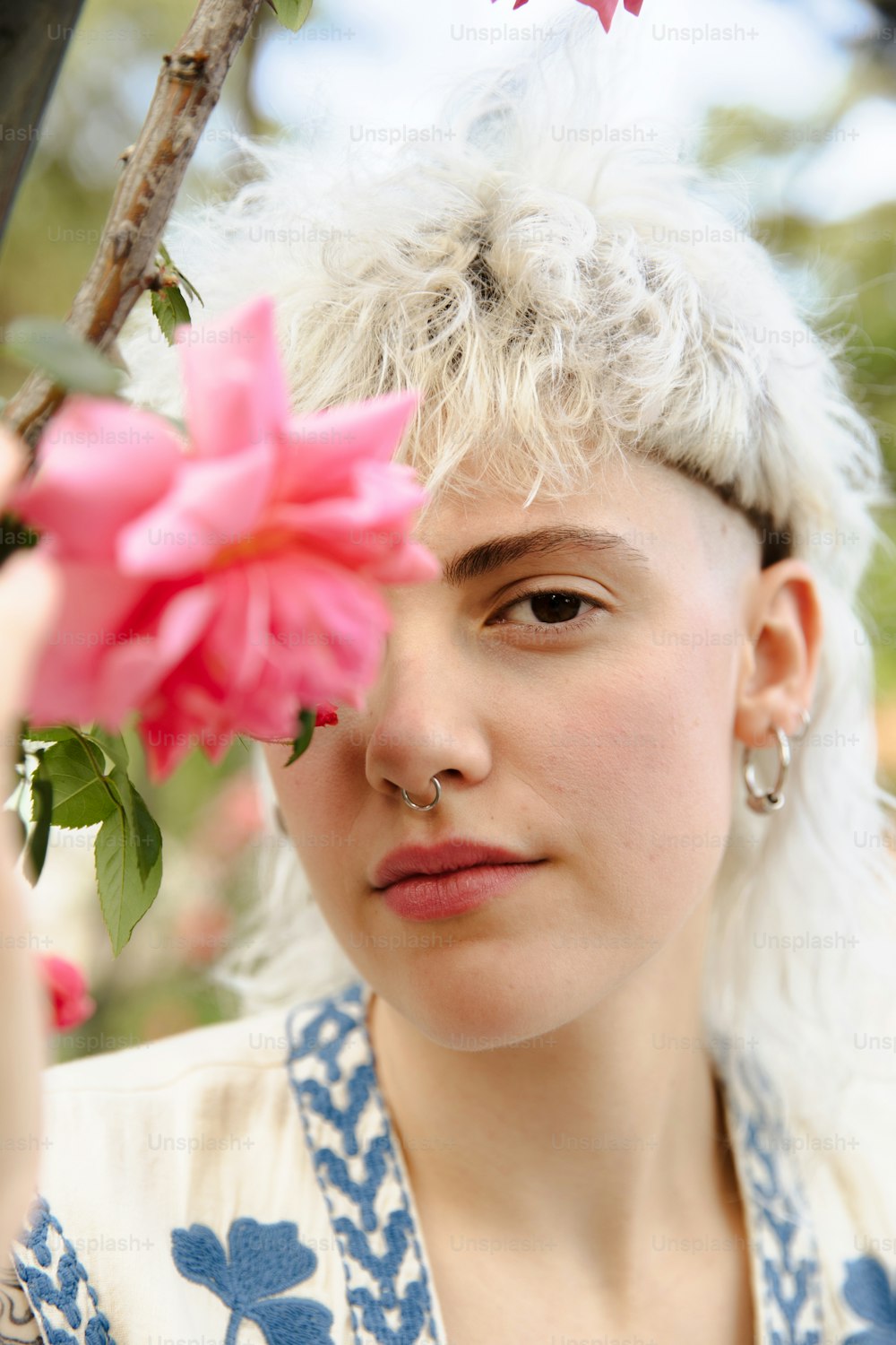 Une femme aux cheveux blancs tenant une fleur rose