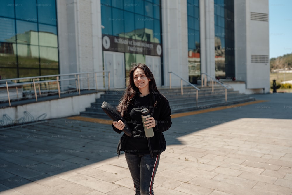 Une femme tenant une planche à roulettes devant un immeuble