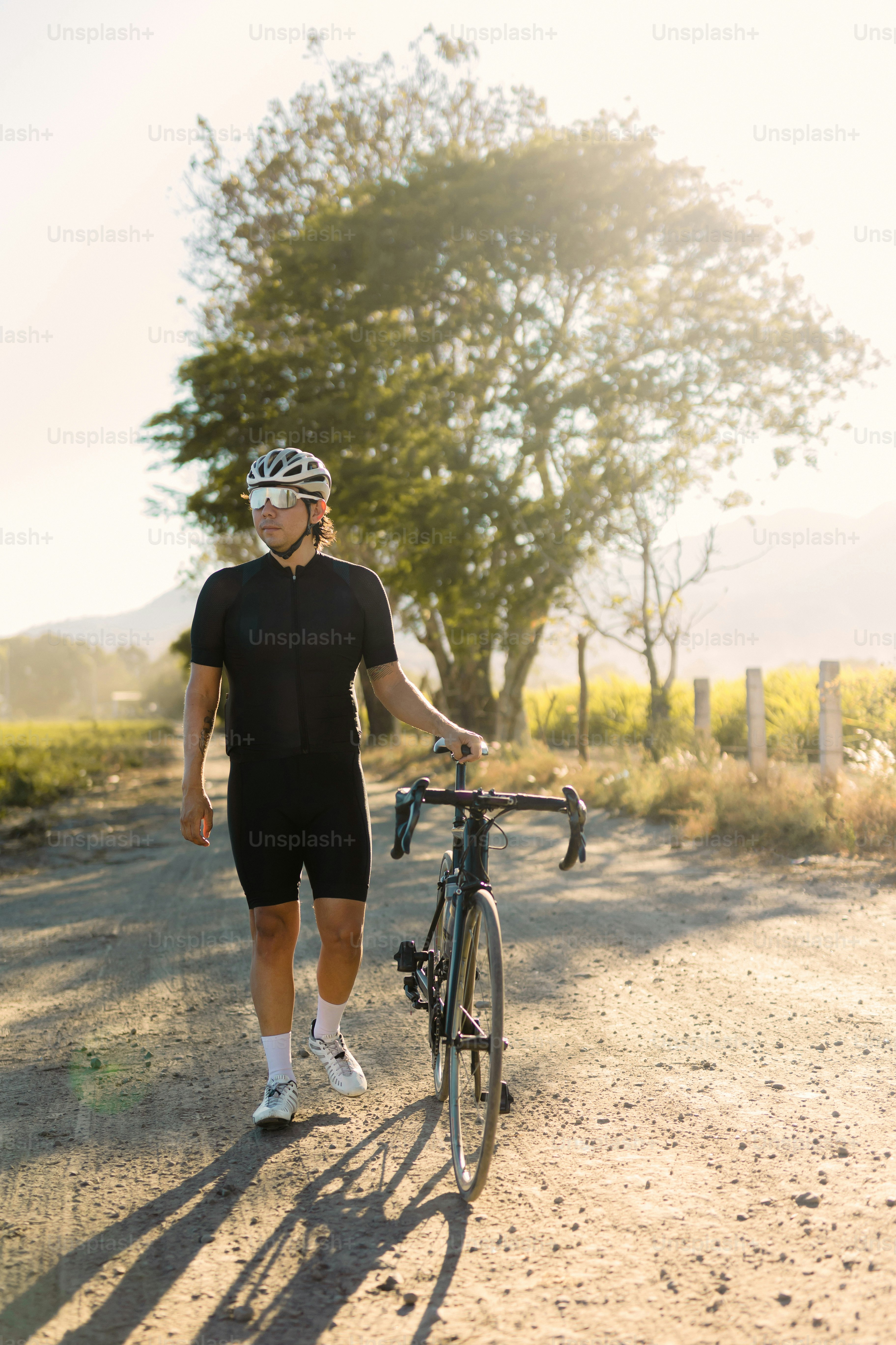 Un uomo che cammina una bicicletta lungo una strada sterrata