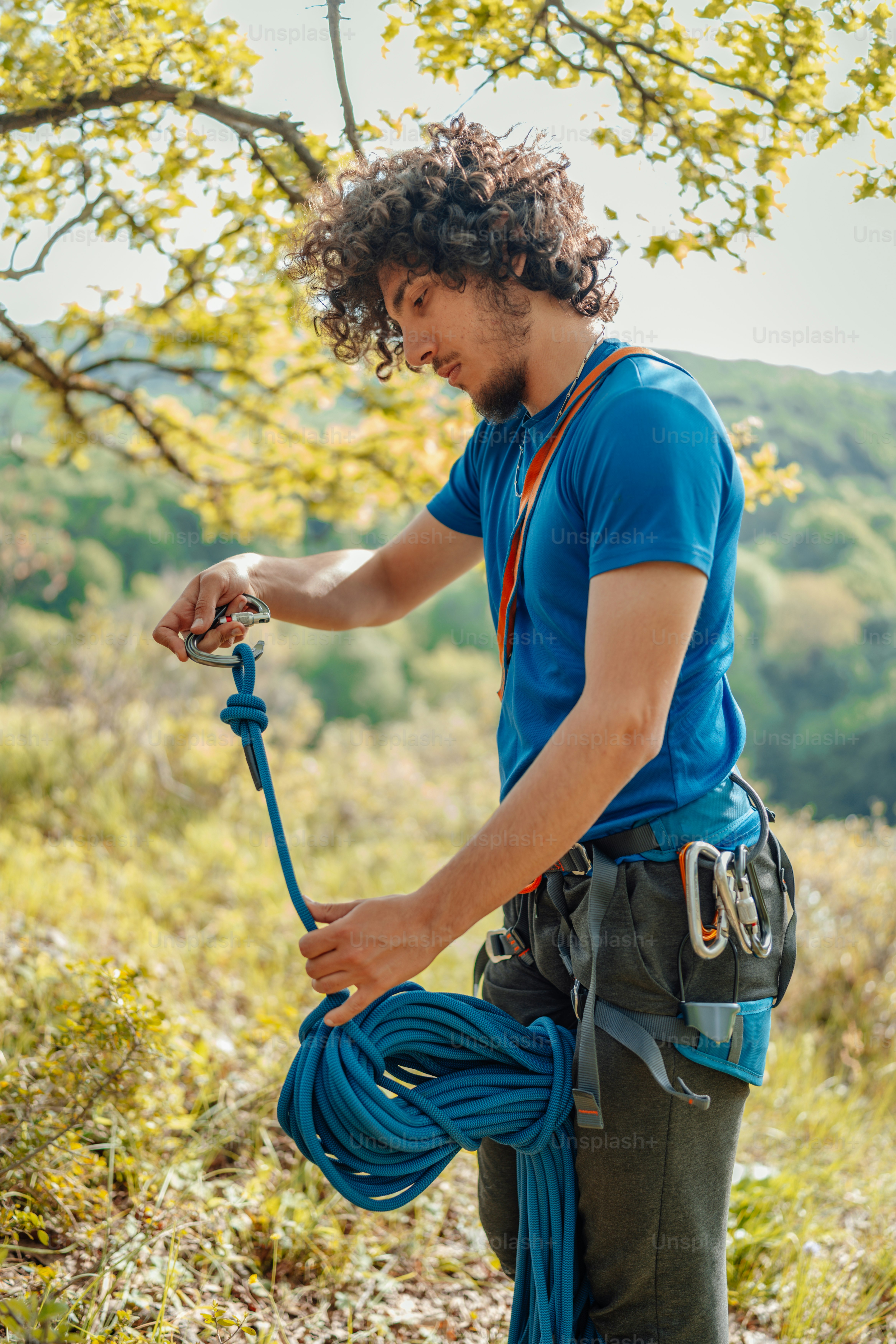 A man holding a rope while standing next to a tree photo – Outdoor ...