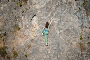 Una donna che si arrampica sul fianco di una montagna