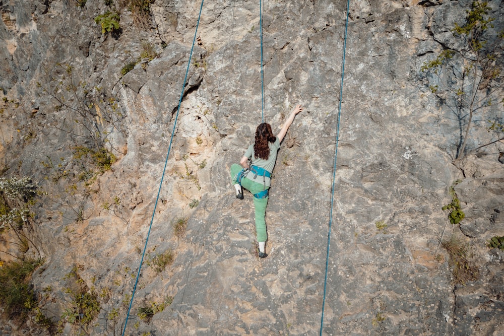 a woman climbing up the side of a mountain