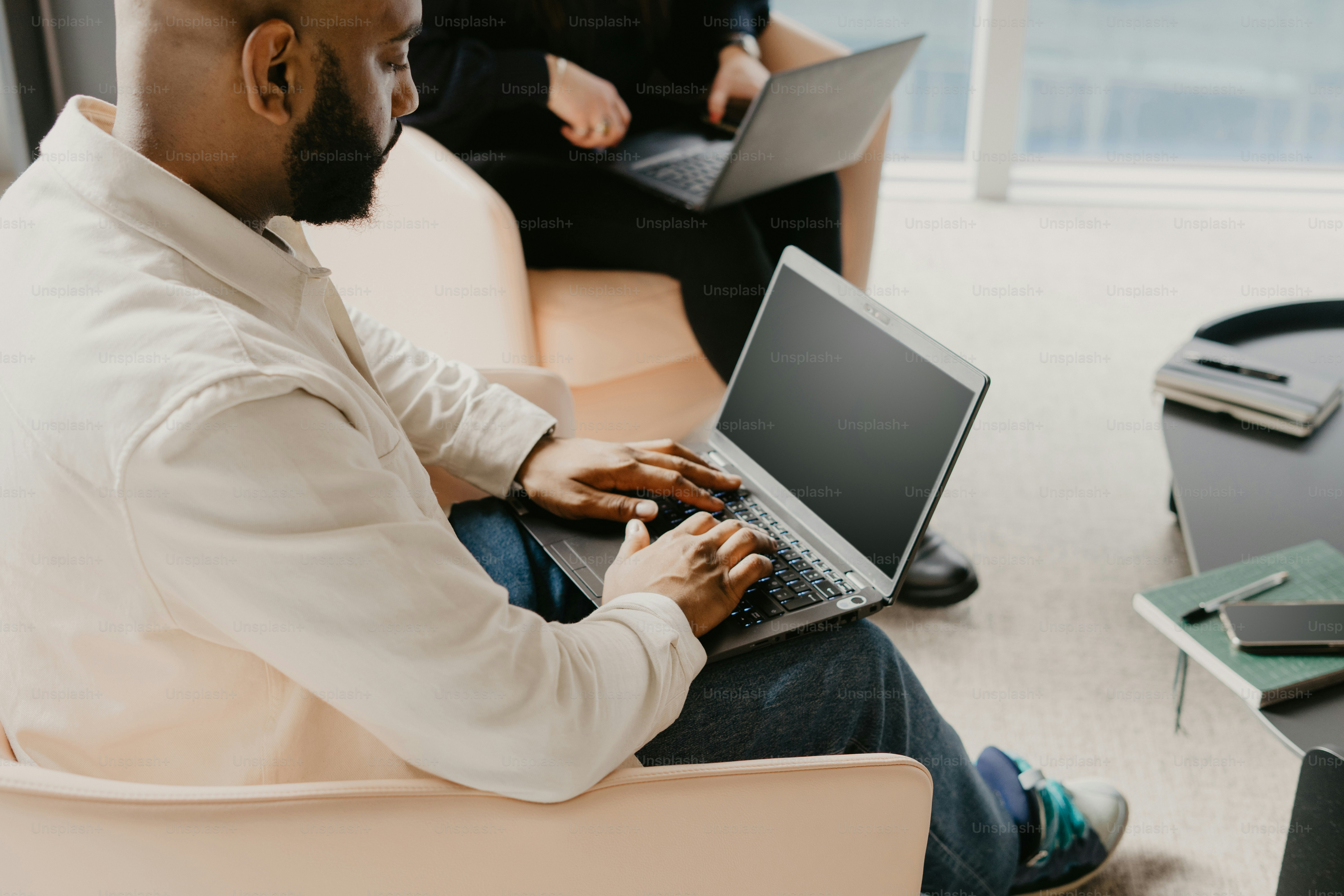 Un hombre sentado en una silla usando una computadora portátil