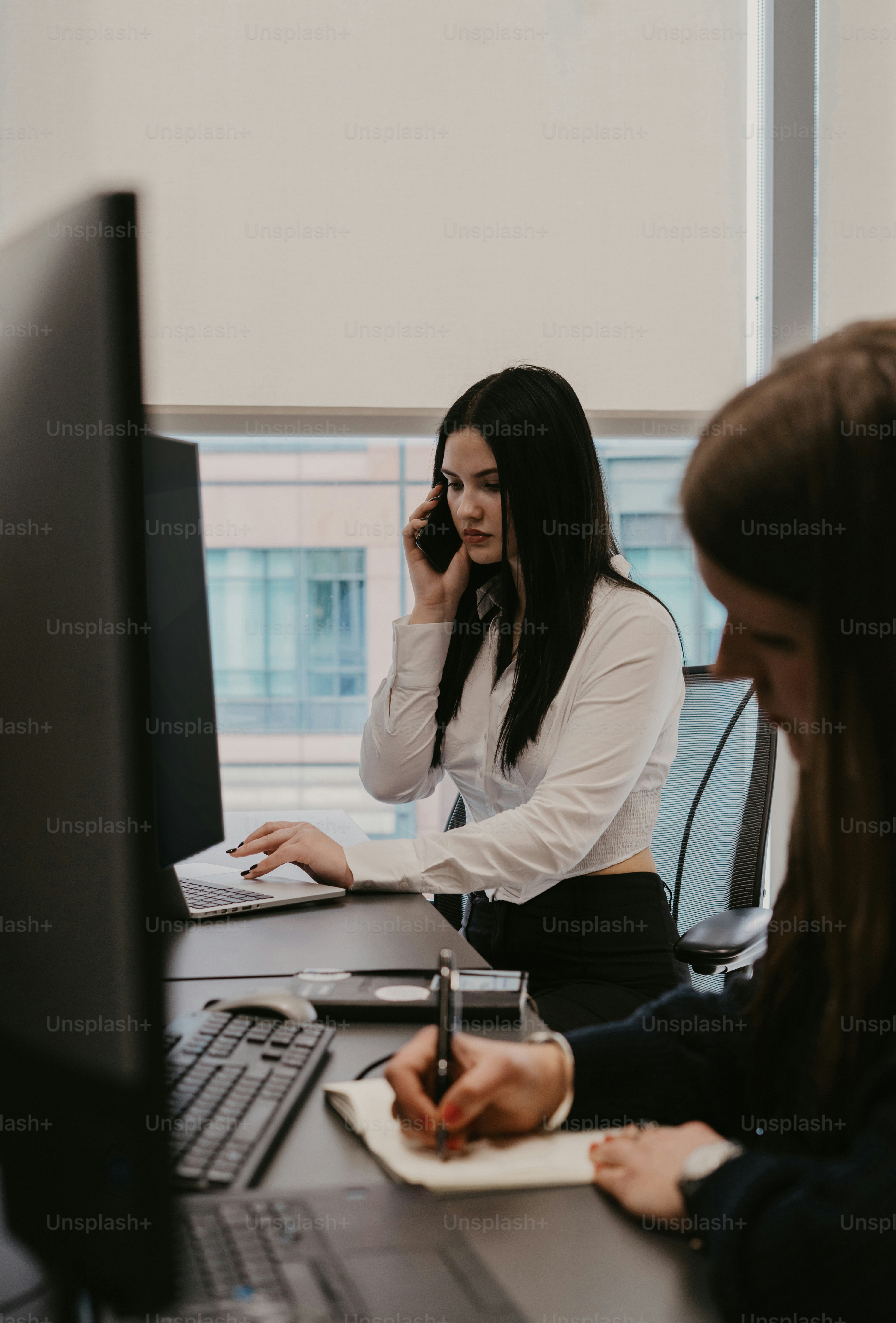 Une femme assise à un bureau parlant au téléphone portable