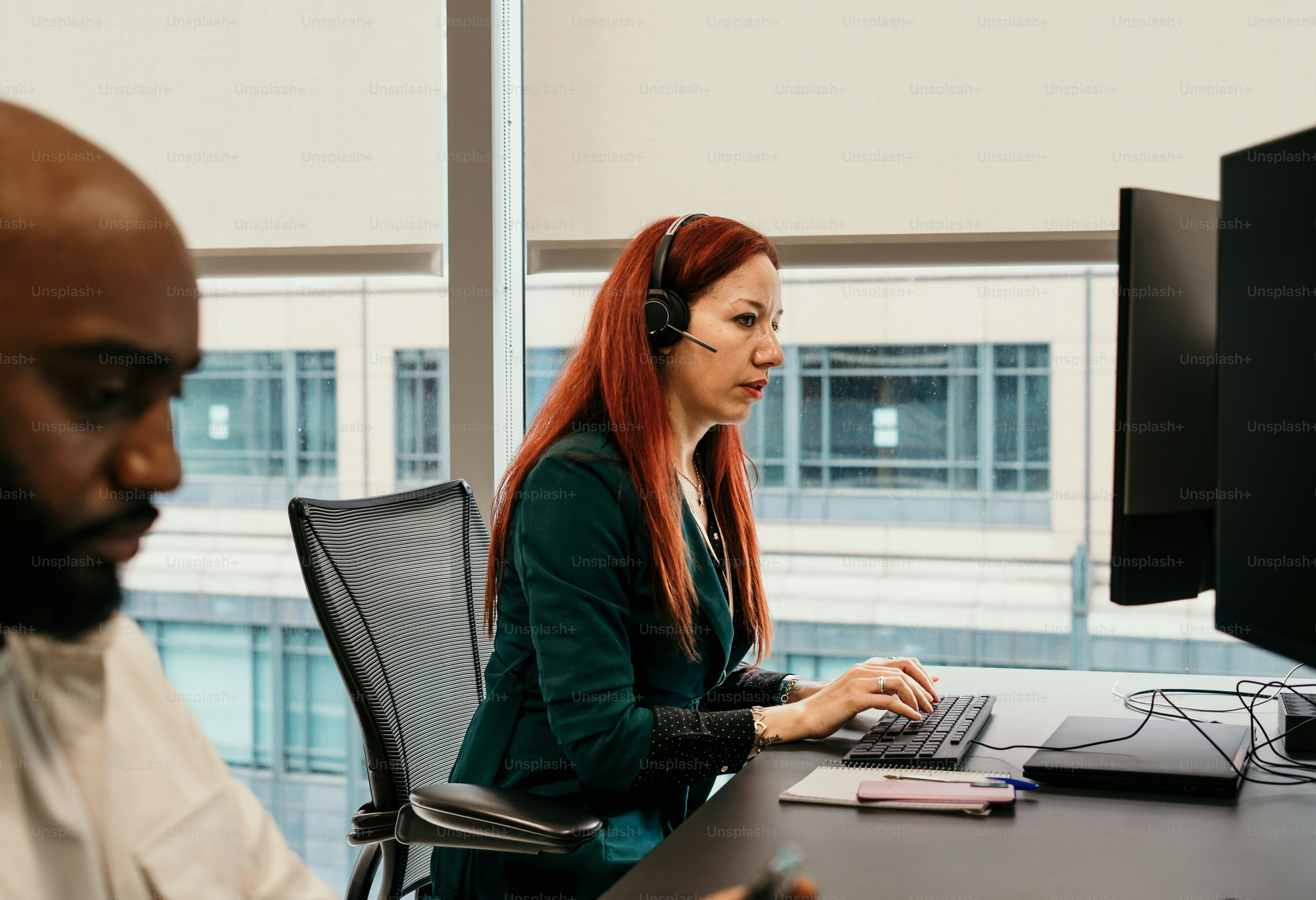 Une femme aux cheveux roux assise devant un ordinateur