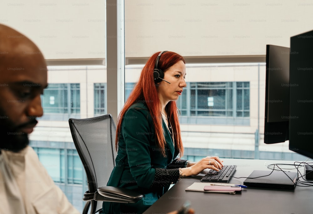 a woman with red hair sitting in front of a computer