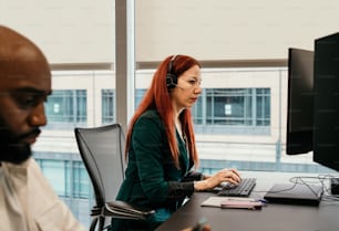 a woman with red hair sitting in front of a computer