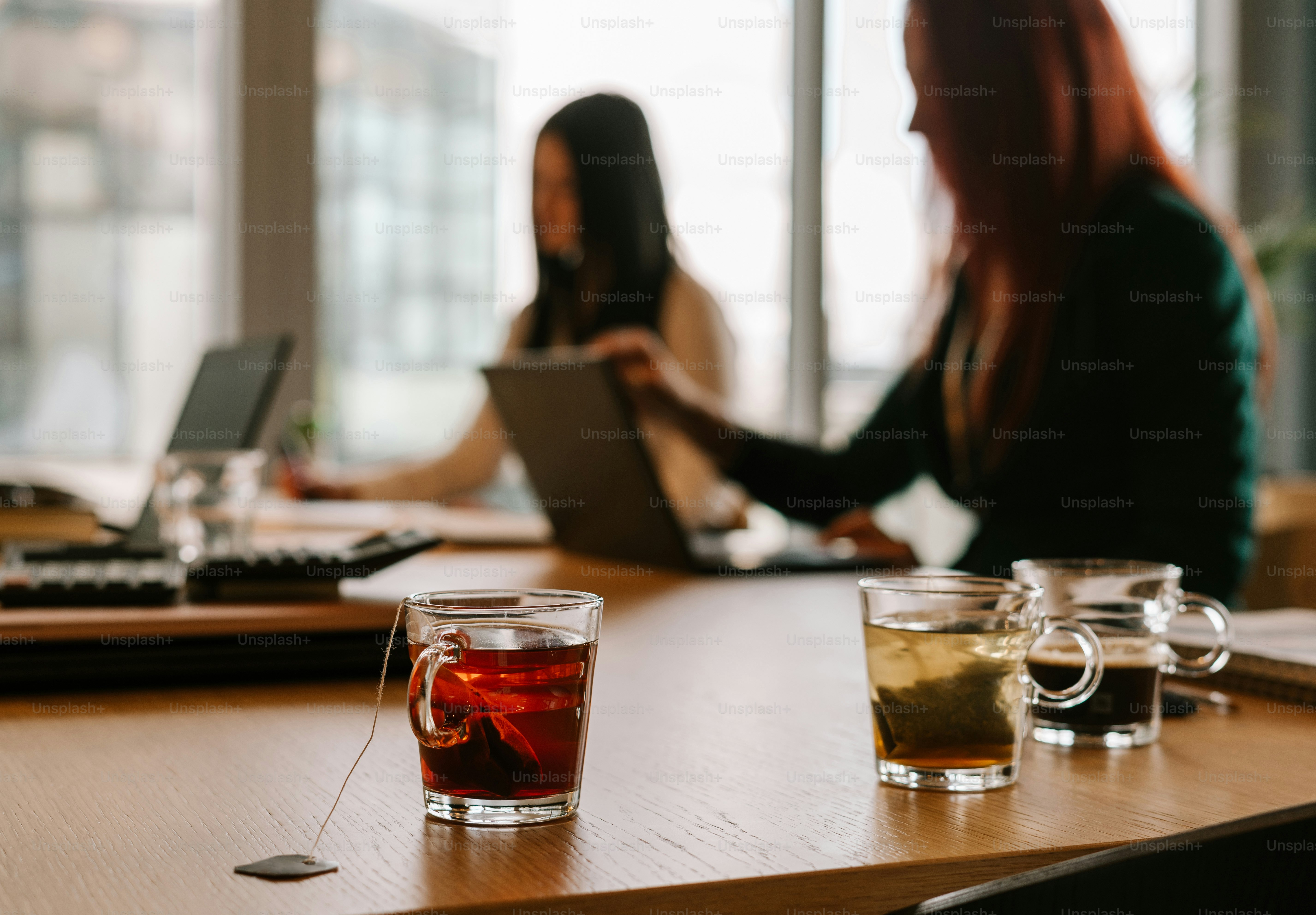 Una mujer sentada en una mesa con un vaso de té frente a ella