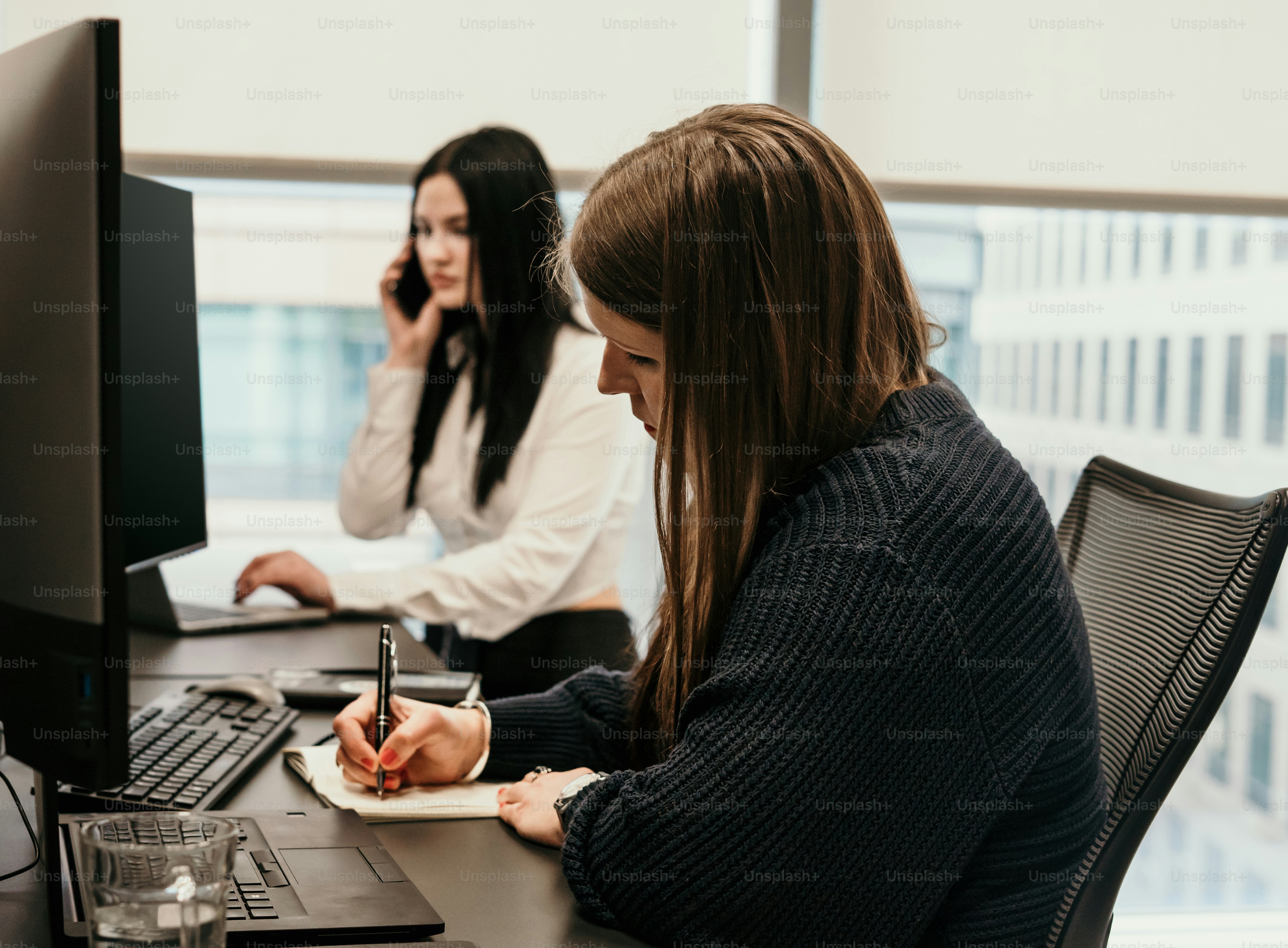 Una mujer sentada en un escritorio escribiendo en un bloc de notas