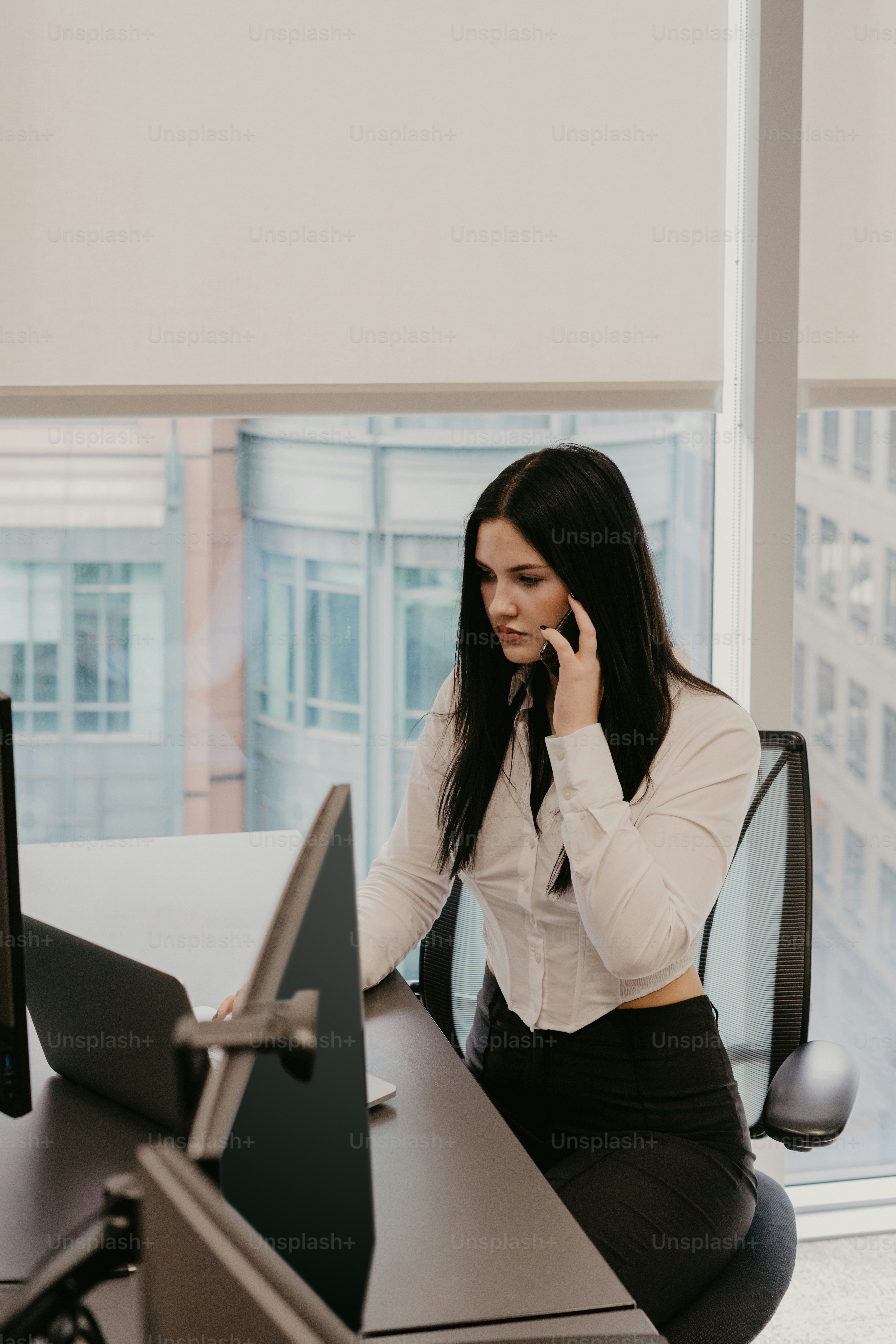 eine frau, die an einem schreibtisch sitzt und mit einem handy telefoniert