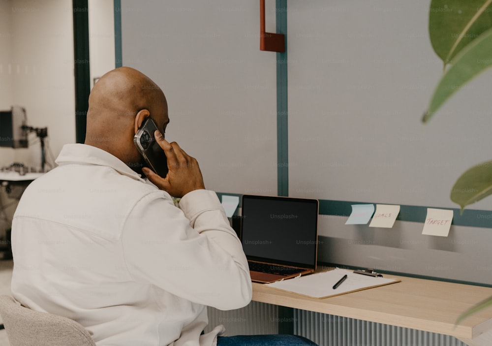 a man sitting at a desk talking on a cell phone