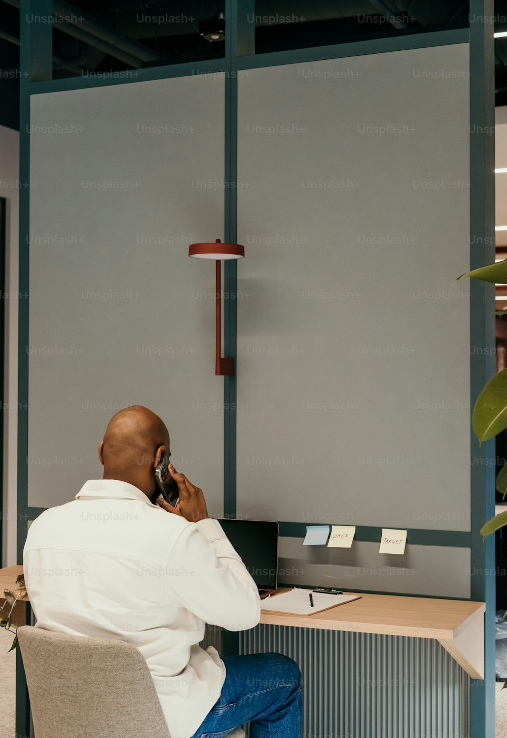 Un hombre sentado en un escritorio hablando por teléfono celular