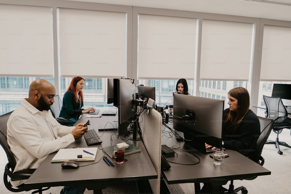 a group of people sitting around a table with computers