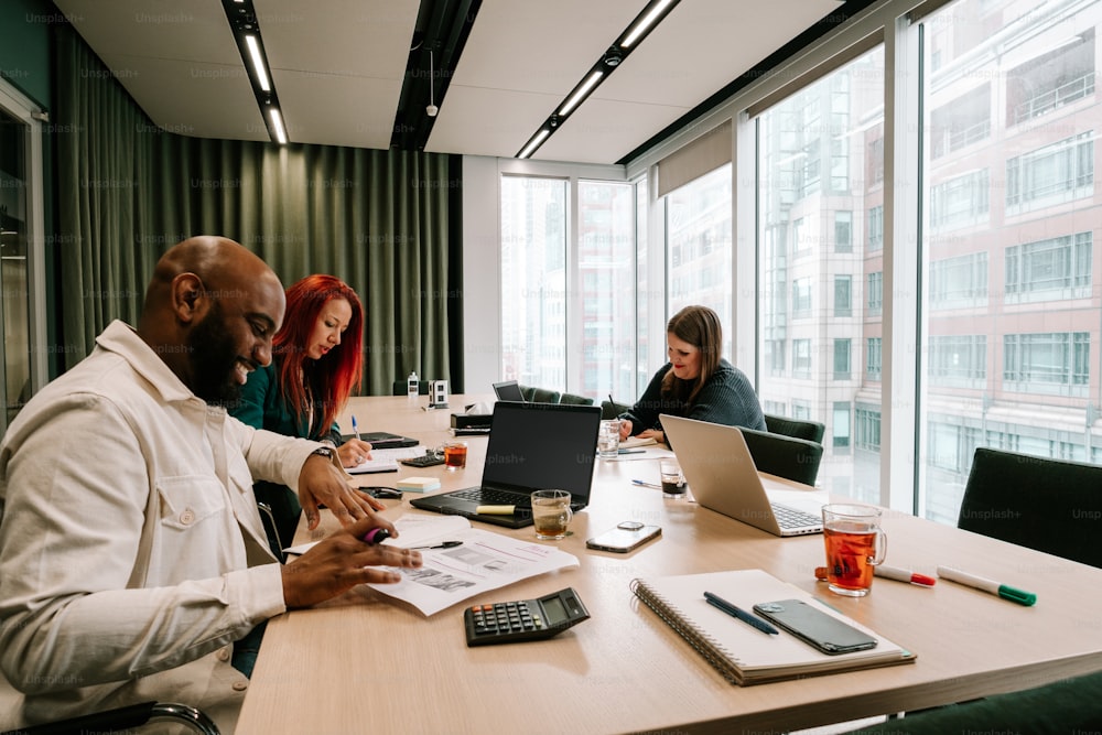 a group of people sitting around a table working on laptops