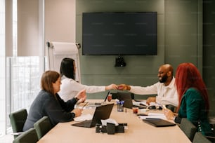 a group of people sitting around a table shaking hands