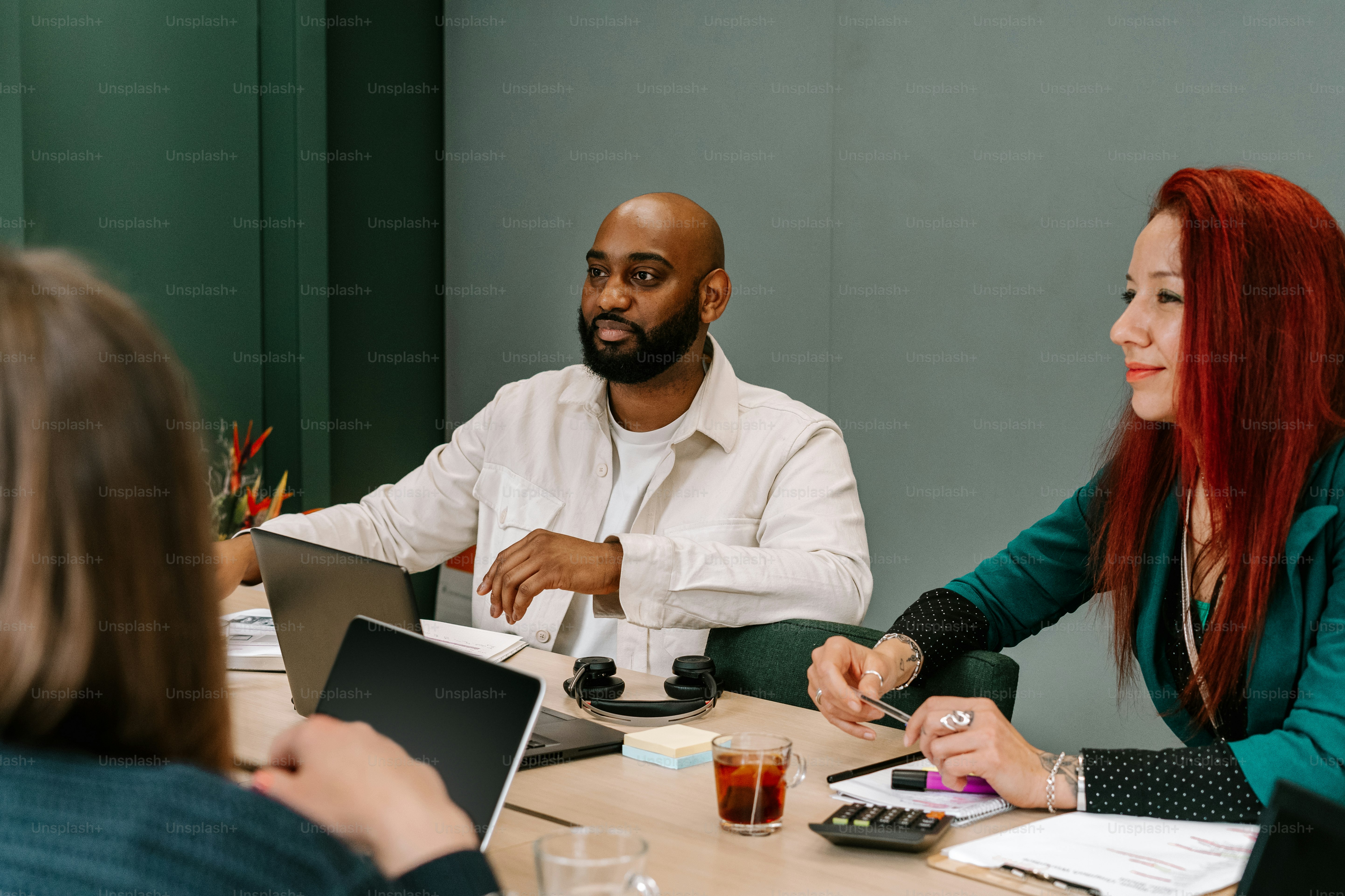 un groupe de personnes assises autour d’une table avec des ordinateurs portables