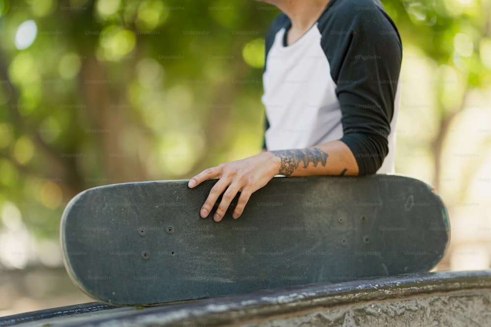 a man with a tattooed arm holding a skateboard