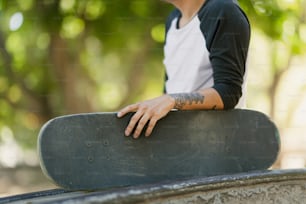 Un uomo con un braccio tatuato che tiene uno skateboard