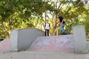 ein paar junge männer, die skateboards eine rampe hinunterfahren