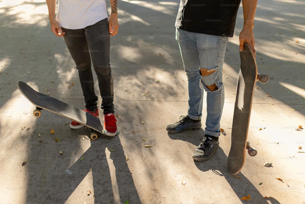 두 사람이 스케이트보드를 들고 나란히 서 있다