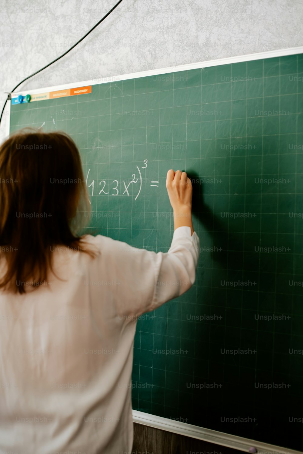 a woman writing on a blackboard in a classroom