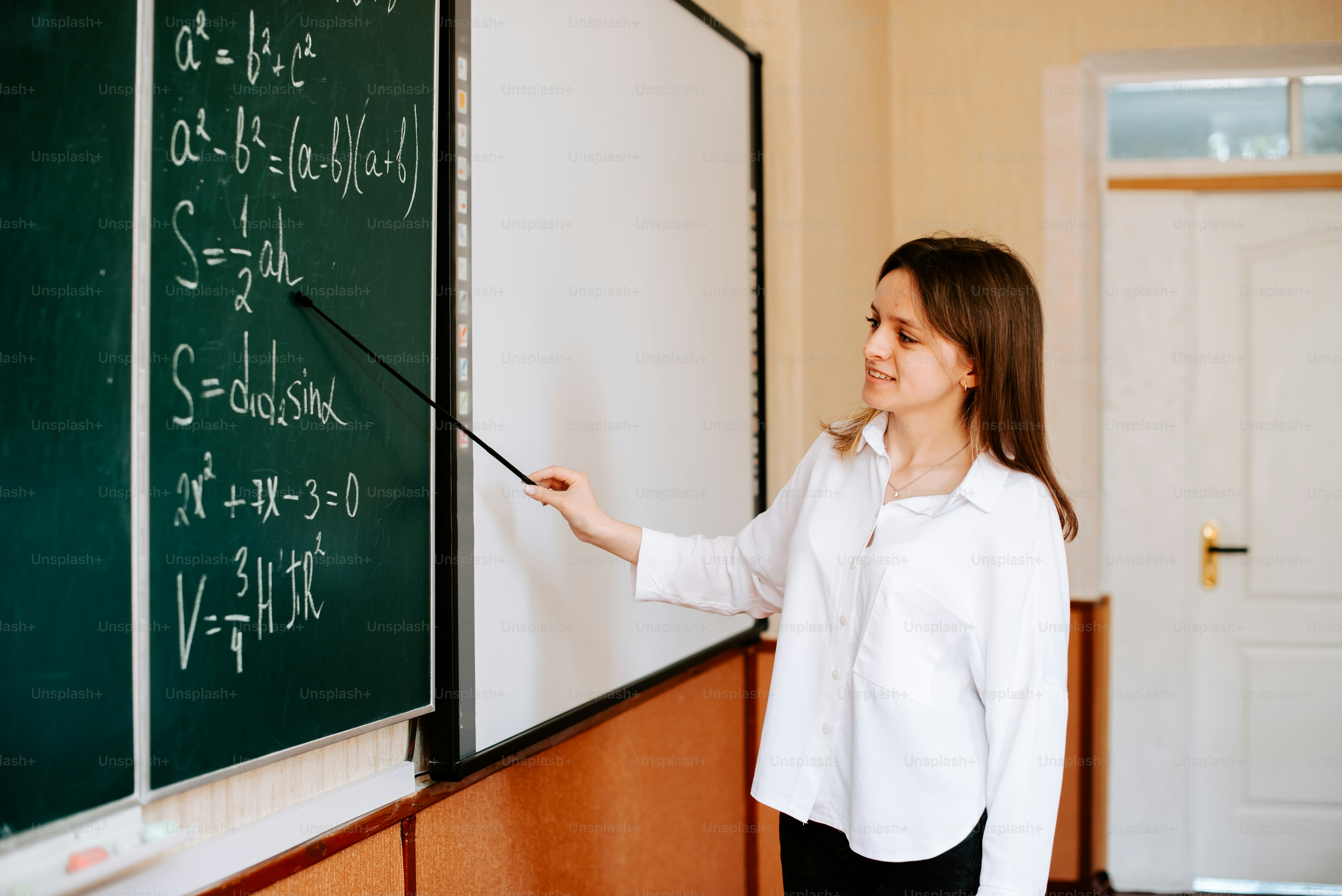 a woman standing in front of a blackboard writing on it
