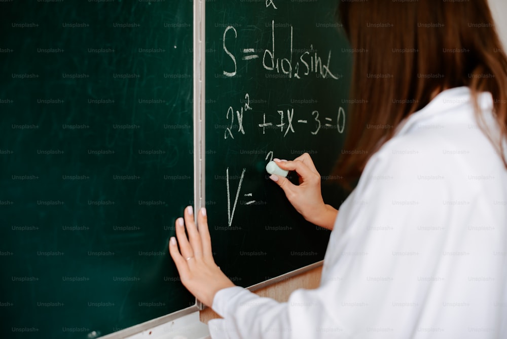 a woman writing on a blackboard with chalk