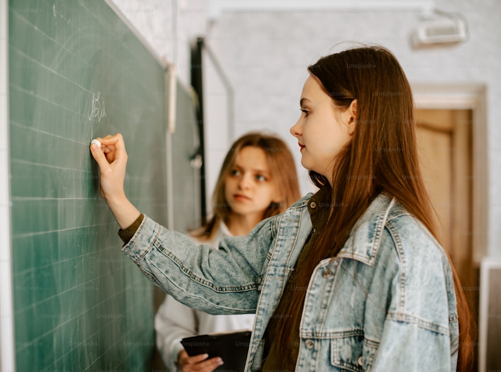 two girls writing on a blackboard in a classroom
