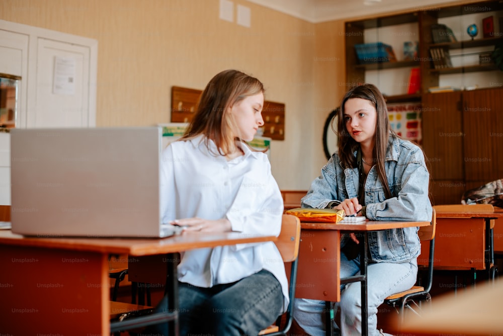 zwei mädchen, sitzen an einem tisch, mit, a, laptop