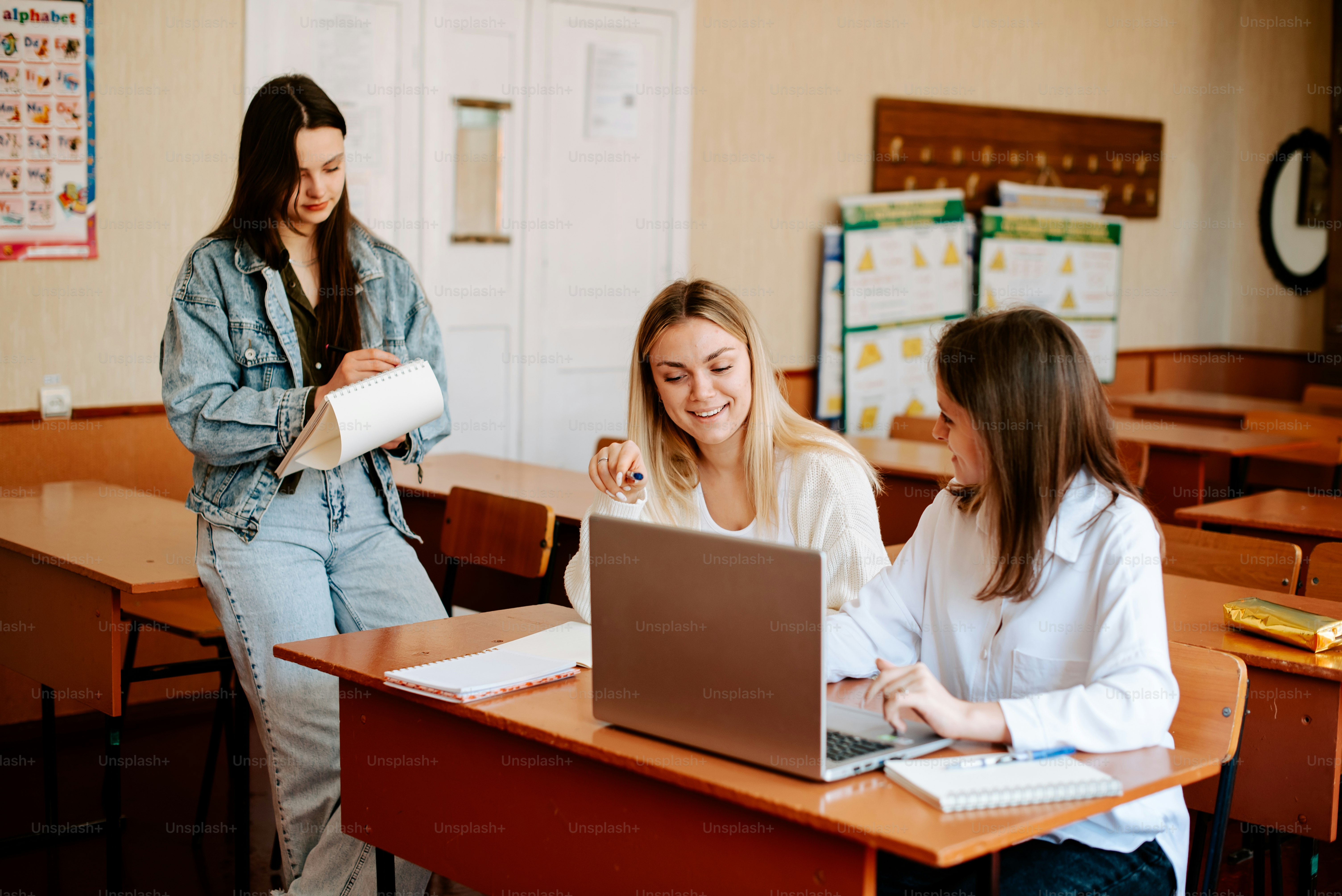 duas meninas sentadas em uma mesa com um laptop na frente delas