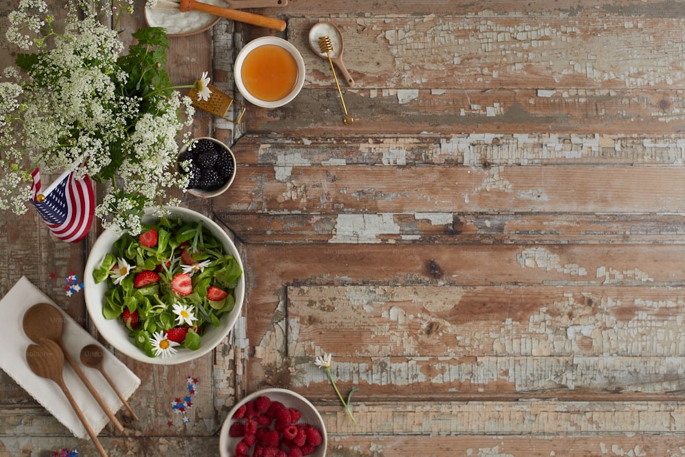 ein Holztisch mit Schüsseln mit Salat und Obst